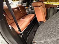 2026-Outlander-PHEV-seating - Kirkland Lake Voice Cargo area of a car with orange-brown leather rear seats folded down, gray carpeting, and a visible seat belt.