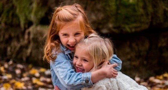 Young girl hugging her little sister