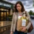 Woman walks outside a Fresh Market with a grocery bag showing a receipt totaling $147.36 on a rainy day.