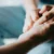 Close-up of hands gently holding another person’s hand, conveying care and comfort in a medical setting.